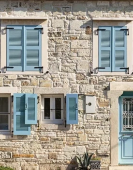 Maison en pierre avec volets et porte d'entrée bleu pastel